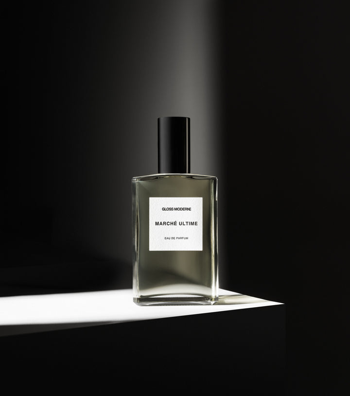 Hero image of a perfume bottle on a white surface with contrast lighting 
