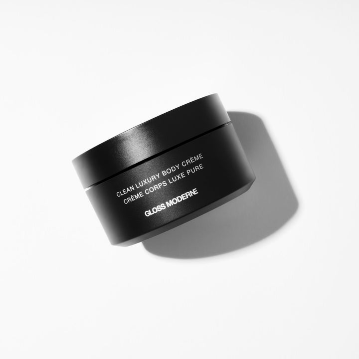 pot of clean luxury body creme on a white table with contrast lighting